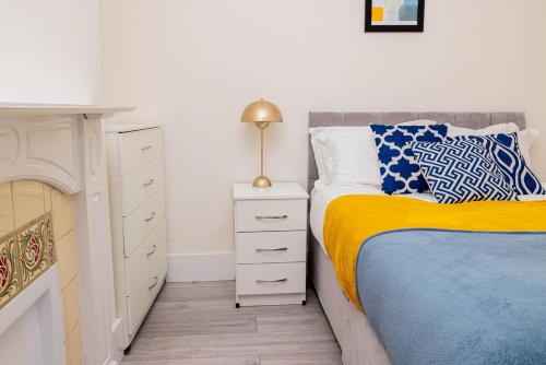 a bedroom with a bed with a yellow blanket and a nightstand at 4-bed house in Kettering for groups and long stays in Kettering