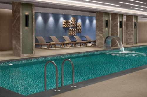 a swimming pool in a hotel with chairs and a fountain at Cappadocia Marriott Hotel in Nevsehir