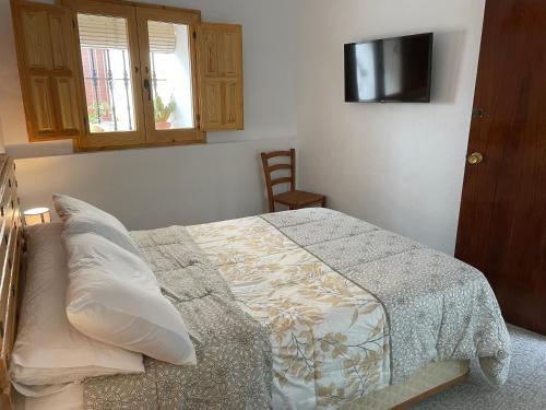 a bedroom with a bed and a television on the wall at Habitación independiente 2 en casa particular in Utrera