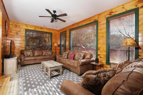 a living room with leather couches and a ceiling fan at Sleeps 22, mountain view, game room, pet friendly! in Sevierville