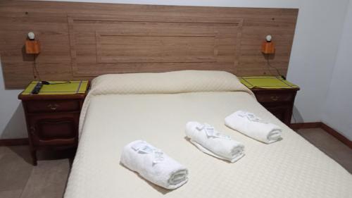 a bed with two pairs of white slippers on it at Mi Lugar in Olavarría
