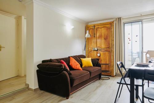a living room with a brown couch and a table at Le Cocon de ville sètois, Clim, patio et garage pour véhicule type golf, Linge de lit et serviettes inclus in Sète
