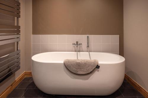 a white bath tub in a bathroom with a tile wall at Riverside Walk in Airton