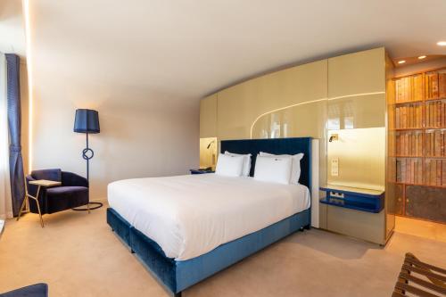 a bedroom with a large white bed and a chair at CBR Boutique Hotel - Coimbra in Coimbra