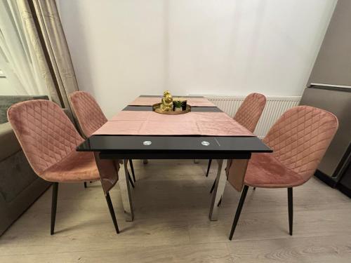 a dining room table with pink chairs and a statue at Dream - Large Apartament with FreeParking in a QuietArea just 10 minutes away from City Center in Bistriţa