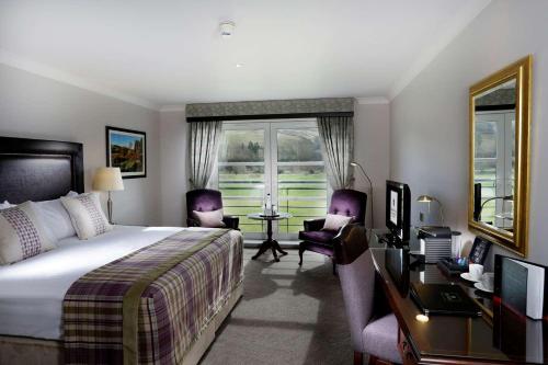 a hotel room with a bed and a desk and chairs at Macdonald Cardrona Hotel, Golf & Spa in Peebles