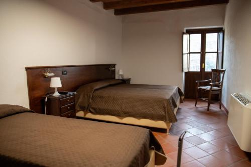 a bedroom with two beds and a chair and a window at Dimora del Borgo Affittacamere in Sangineto