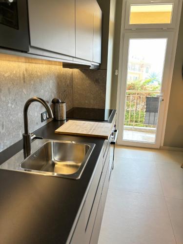 une cuisine avec un évier en acier inoxydable et une fenêtre dans l'établissement NICE La Palmeraie Pool BEACH AC, à Nice