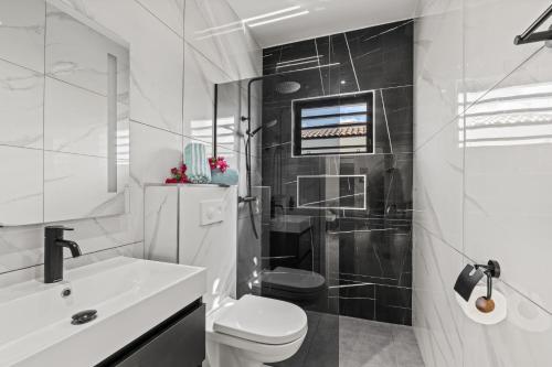 a white bathroom with a toilet and a sink at Villa Mambolicious in Willemstad