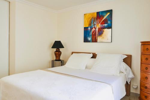 une chambre avec un lit blanc et un tableau au mur dans l'établissement Le Cocon de ville sètois, Clim, patio et garage pour véhicule type golf, Linge de lit et serviettes inclus, à Sète