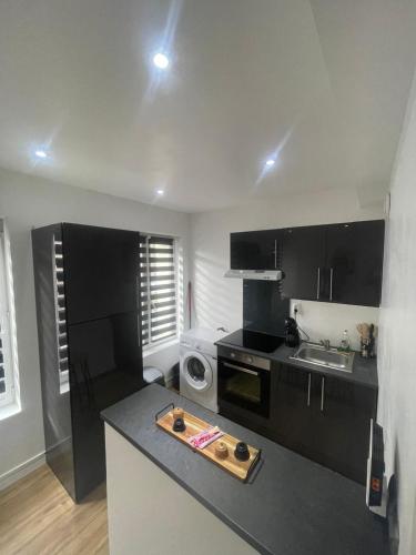 une cuisine avec des armoires noires et un comptoir dans l'établissement F2 centre-ville Netflix, Disney plus, à Amiens