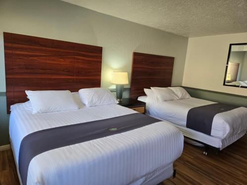 a hotel room with two beds and a mirror at Sage Motel in Vernal