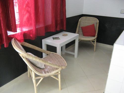 a room with two chairs and a table and a red curtain at Auberge Tinit in Er Rachidia