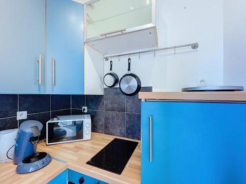une cuisine avec des placards bleus et un four micro-ondes sur un comptoir dans l'établissement Havre d'Esther, à Nancy