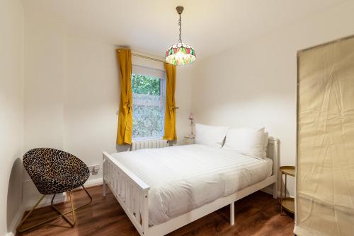 a bedroom with a bed and a window and a chair at Cosy 1-Bed Flat by Central London in London
