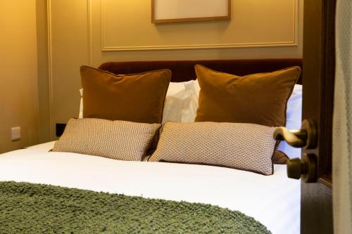 a bed with brown pillows and white sheets at The Wheatley Arms in Ilkley