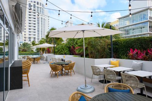 a patio with tables and chairs and an umbrella at Hyatt Centric South Beach Miami in Miami Beach