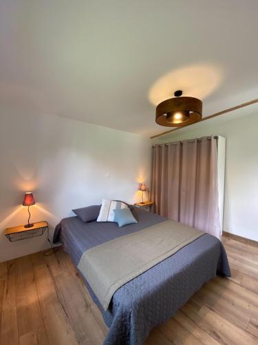 - une chambre avec un lit et deux lampes sur deux tables dans l'établissement Evasion forestiere a Camors Lambel, à Camors