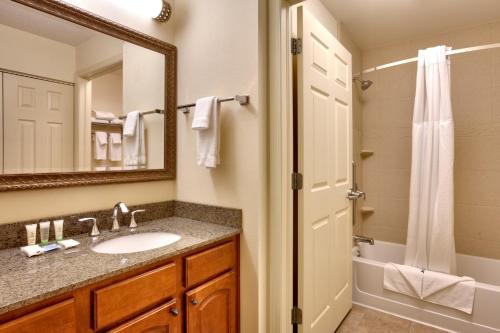 a bathroom with a sink and a mirror and a shower at Staybridge Suites Omaha 80th and Dodge by IHG in Omaha