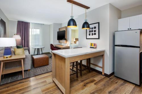 a kitchen and living room with a refrigerator and a table at Staybridge Suites Omaha 80th and Dodge by IHG in Omaha
