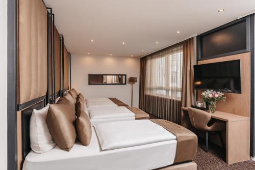 a hotel room with four beds and a desk at Hotel Unique Majestic in Dortmund