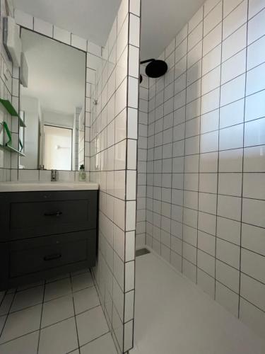 La salle de bains est pourvue de carrelage blanc, d'un lavabo et d'un miroir. dans l'établissement Gigaro Sylvabelle Sea Zen 2, à La Croix-Valmer