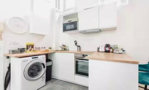 a kitchen with white cabinets and a washer and dryer at Cosy and Modern near Champs-Élysées - Arc de Triomphe in Paris
