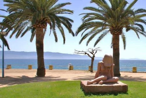 une statue d'une femme assise sur un banc à côté des palmiers dans l'établissement Casamea - Escapade en bord de mer, Accès plage, à Ajaccio