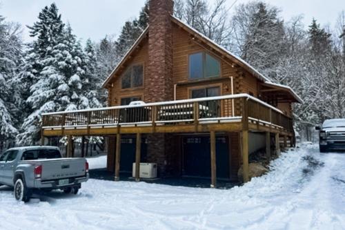 a log cabin with a deck in the snow at Mooseleuk Lodge in The Highlands