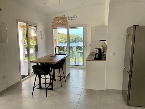 y cocina con mesa, sillas y nevera. en Appartement Kay Nephile - vue mer - Grande Anse, en Les Anses-dʼArlet