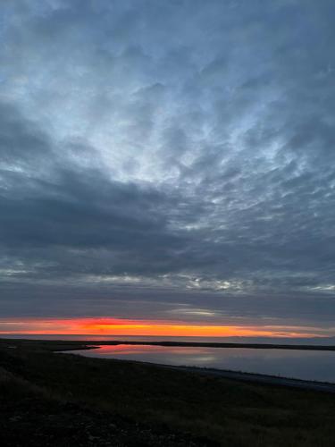 a sunset over the water with a cloudy sky at Kirkjufell View Cottages in Grundarfjordur