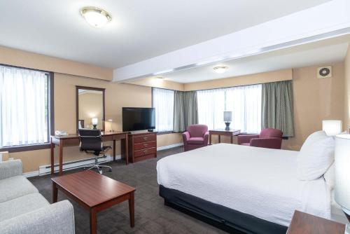 a hotel room with a bed a desk and a tv at Sandman Hotel Castlegar in Castlegar