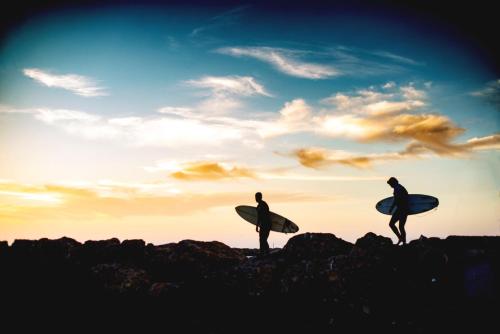 two people walking on top of a mountain with surfboards at Staybridge Suites Oxnard - River Ridge by IHG in Oxnard