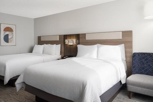 two beds in a hotel room with a chair at Holiday Inn Express & Suites Midwest City by IHG in Midwest City