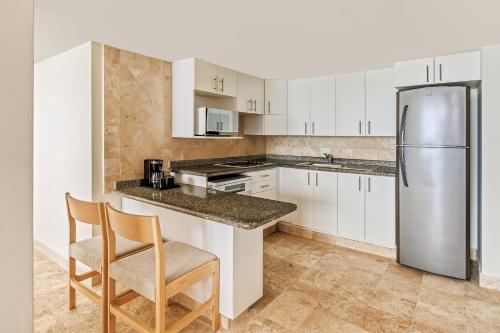 a kitchen with white cabinets and a stainless steel refrigerator at Fiesta Americana Acapulco Villas in Acapulco