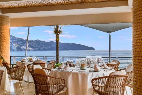 a dining room with tables and chairs with a view of the ocean at Fiesta Americana Acapulco Villas in Acapulco