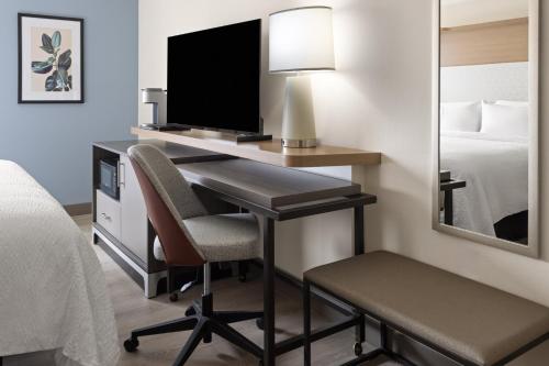 a room with a desk with a television and a bed at Holiday Inn & Suites Richmond West End by IHG in Richmond