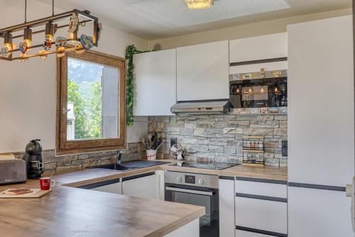 - une cuisine avec des placards blancs et un mur en pierre dans l'établissement Appartement Cosy - 1 à 2 chambres proche thermes et ski, à Saint-Gervais-les-Bains