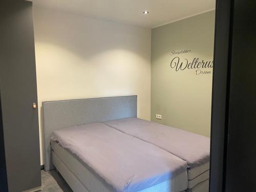 a bed in a bedroom with a sign on the wall at de Loeiende koe in Liessel