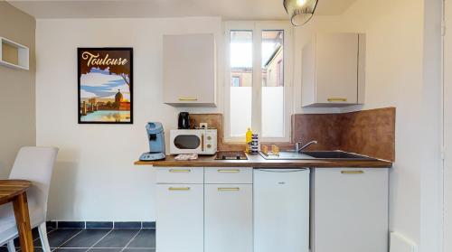 une cuisine avec des armoires blanches et un micro-ondes dans l'établissement Studio Pouvillon proche Zenith - Centre Toulousain, à Toulouse