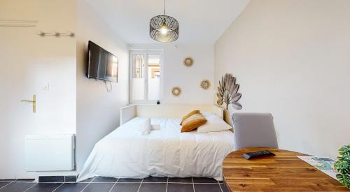 une chambre blanche avec un lit et une table dans l'établissement Studio Pouvillon proche Zenith - Centre Toulousain, à Toulouse