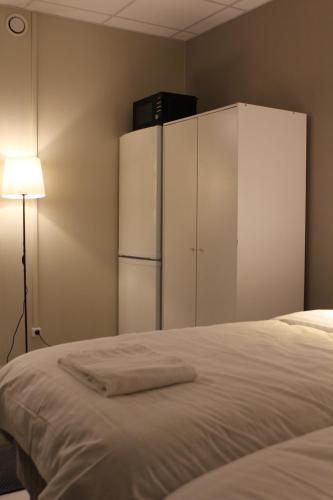 a bedroom with a bed with a refrigerator and a lamp at Hotell Bromma in Stockholm