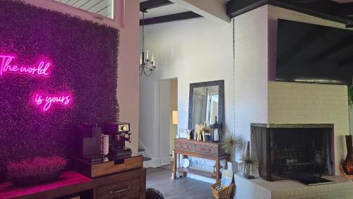 a living room with a purple wall with a tv at 904 Nomad's Nest Mid-Century modern entertainment home with cabin vibes, 2 MEGA gamerooms, pingpong, pooltable, gym, patio in Jacksonville