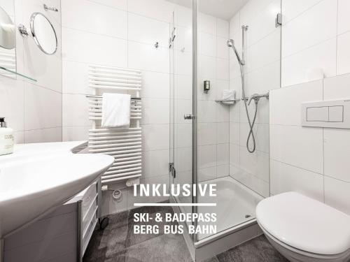 a bathroom with a shower and a toilet and a sink at Hotel Belvedere Scuol in Scuol