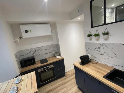 une cuisine avec des appareils et des plantes en noir et blanc sur le mur dans l'établissement T2 Haut de Gamme en Hyper Centre, Rénové Avec Soin, à Nantes