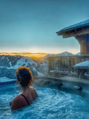 a woman sitting in a hot tub with a view of a mountain at Chalet avec jacuzzi - 150 m des remontées in Morzine