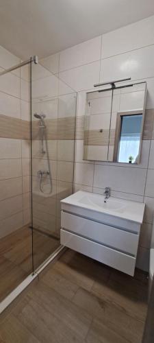 a bathroom with a sink and a shower and a mirror at Aqua apartmanház Gyenesdiás in Gyenesdiás