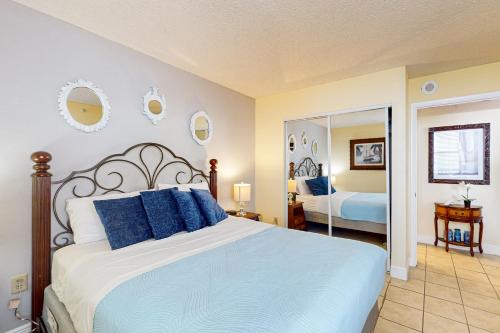 a bedroom with a bed with blue pillows and a mirror at Lover's Key Oasis in Fort Myers Beach