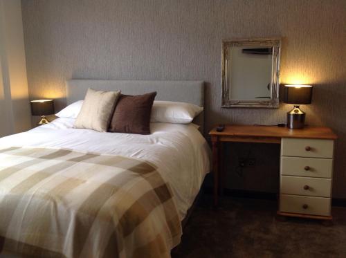 a bedroom with a bed and a table with a mirror at Rooms @ Number Six in Oakham