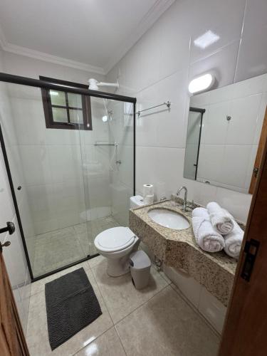 a bathroom with a shower and a toilet and a sink at Suítes Betel in Paraty